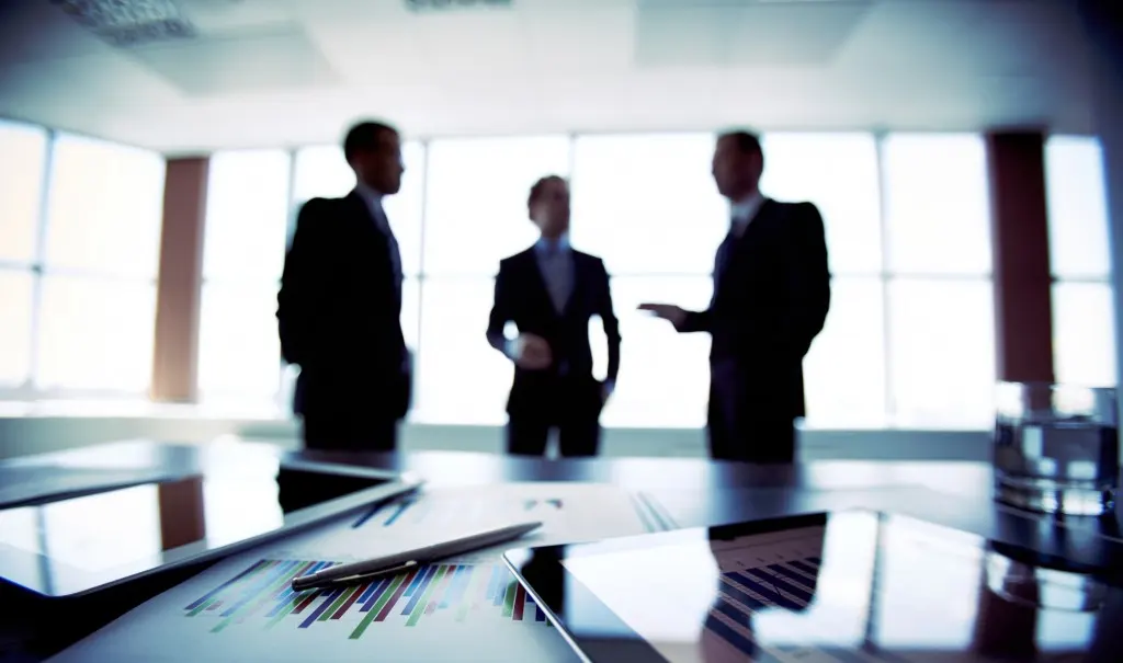 Three business individuals in a room organising financial information.